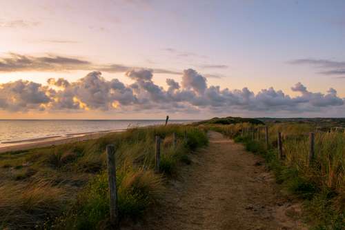Foto groot bekijken: Zandpad door de duinen naar zee, 's avonds