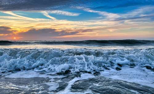 Foto groot bekijken: Golven op het strand bij zonsondergang