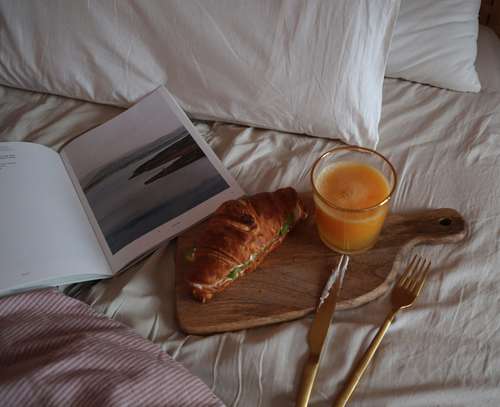 Foto groot bekijken: Ontbijt op bed met een croissant en jus d'orange